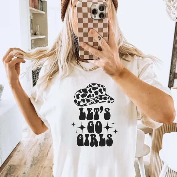 Person wearing a white t-shirt with 'Let's Go Girls' text and a leopard print hat graphic.