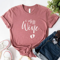 Mauve graphic tee with 'I miss wine' text and baby feet, styled with denim shorts and sneakers