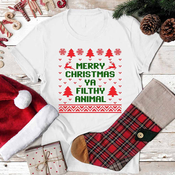 White t-shirt with Christmas-themed text, surrounded by festive items on a wooden surface.