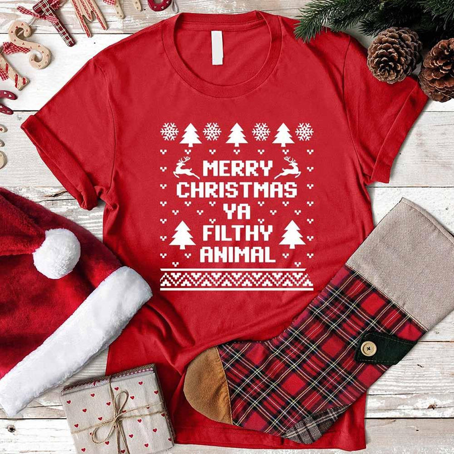 Red t-shirt with Christmas-themed text, surrounded by festive items on a wooden surface.
