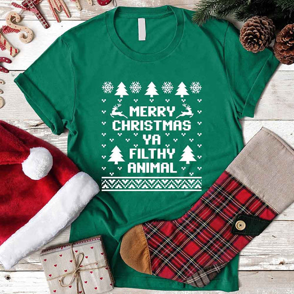 Green t-shirt with Christmas-themed text and graphics on a wooden surface with festive items.