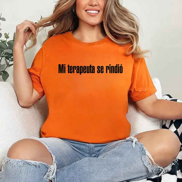 May include a person wearing a orange colored graphic t-shirt with the Spanish phrase “Mi Terapeuta Se Rindió”.