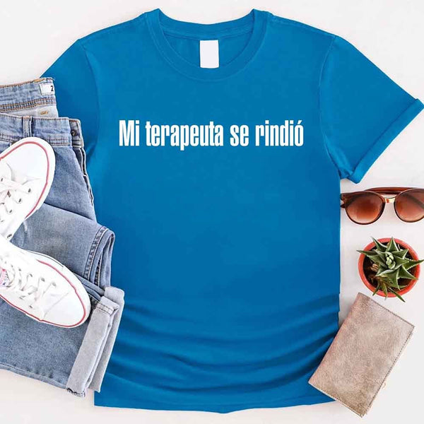 May include a person wearing a sapphire colored graphic t-shirt with the Spanish phrase “Mi Terapeuta Se Rindió”.