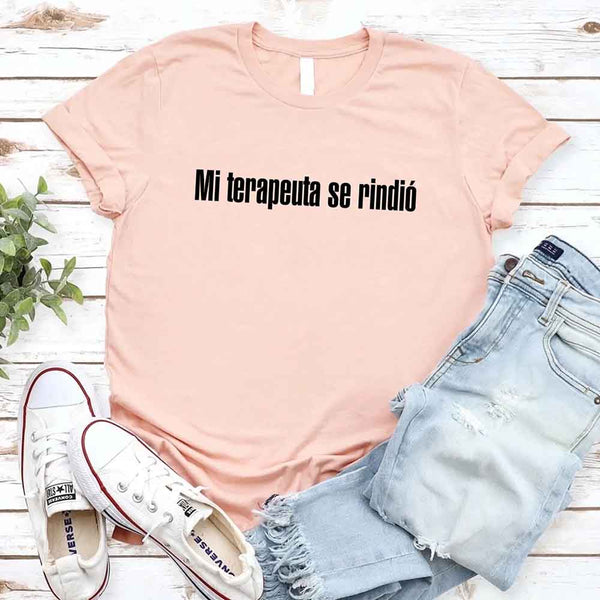 May include a person wearing a peach colored graphic t-shirt with the Spanish phrase “Mi Terapeuta Se Rindió”.