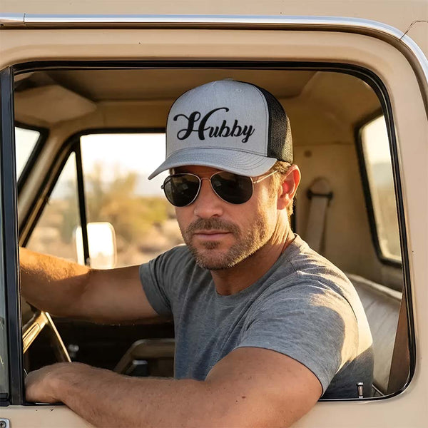 May include an embroidered trucker hat featuring the word “Hubby” stitched in clean, classic lettering on the front panel, designed with a structured crown and breathable mesh back for a timeless wedding or anniversary accessory.