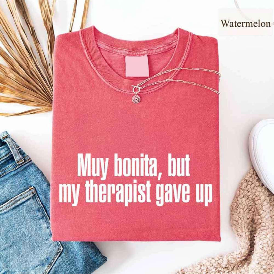 May include a person wearing a watermelon colored sarcastic graphic t-shirt with the phrase “Muy Bonita But My Therapist Gave Up”.
