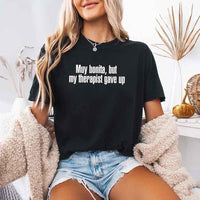 May include a person wearing a black colored sarcastic graphic t-shirt with the phrase “Muy Bonita But My Therapist Gave Up”.

