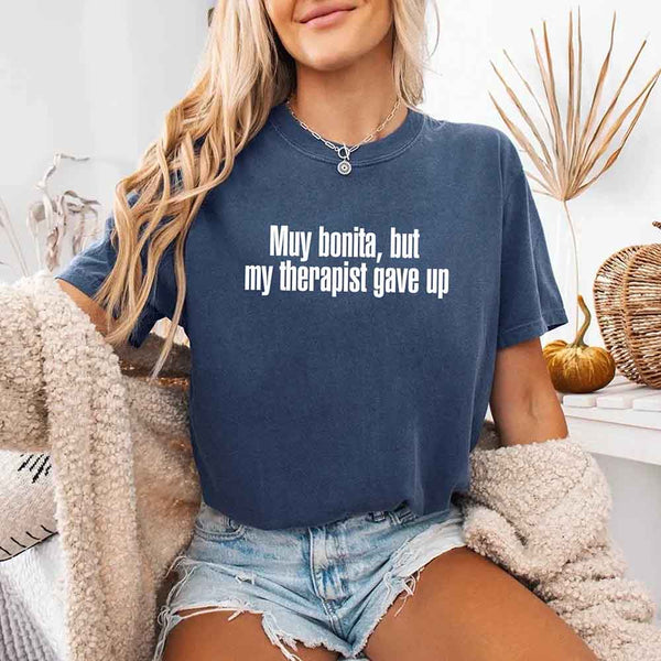 May include a person wearing a denim colored sarcastic graphic t-shirt with the phrase “Muy Bonita But My Therapist Gave Up”.
