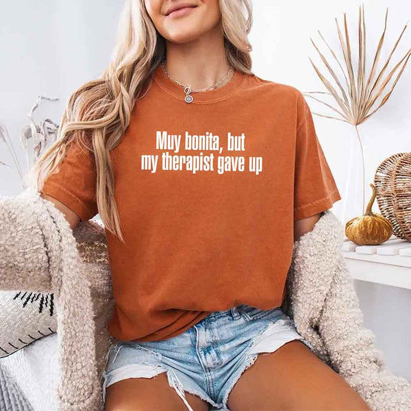 May include a person wearing a yam colored sarcastic graphic t-shirt with the phrase “Muy Bonita But My Therapist Gave Up”.
