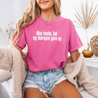 May include a person wearing a crunchberry colored sarcastic graphic t-shirt with the phrase “Muy Bonita But My Therapist Gave Up”.
