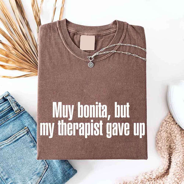 May include a person wearing an expresso colored sarcastic graphic t-shirt with the phrase “Muy Bonita But My Therapist Gave Up”.
