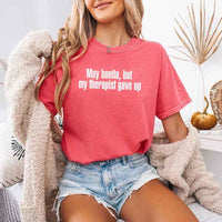 May include a person wearing a watermelon colored sarcastic graphic t-shirt with the phrase “Muy Bonita But My Therapist Gave Up”.
