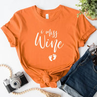 Orange custom tee with 'I miss Wine' text and baby footprints, styled with denim shorts.