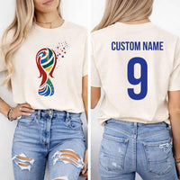 May include a person wearing a cream 2026 World Cup T-shirt featuring bold soccer graphic and relaxed fit.