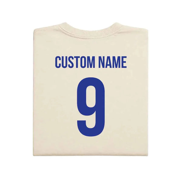 May include a person wearing a cream 2026 World Cup T-shirt featuring bold soccer graphic and relaxed fit.