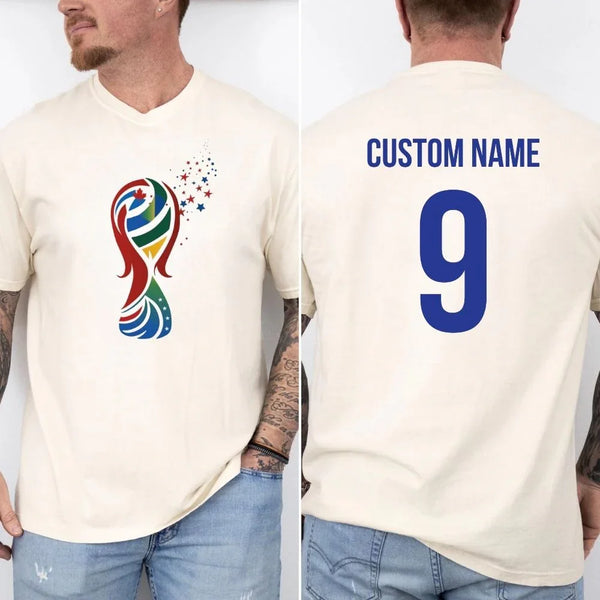 May include a person wearing a cream 2026 World Cup T-shirt featuring bold soccer graphic and relaxed fit.