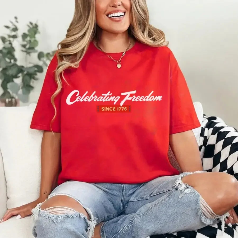 Person wearing a red t-shirt with 'Celebrating Freedom Since 1776' text, sitting on a couch.