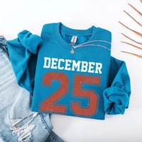 May include a retro-style Christmas sweatshirt featuring bold varsity lettering that reads “December 25” in green and red. The design has a vintage, slightly distressed look, giving it a nostalgic holiday feel perfect for festive winter wear.