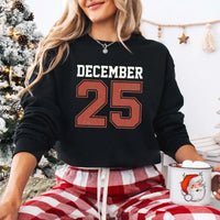 May include a retro-style Christmas sweatshirt featuring bold varsity lettering that reads “December 25” in green and red. The design has a vintage, slightly distressed look, giving it a nostalgic holiday feel perfect for festive winter wear.