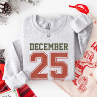 May include a retro-style Christmas sweatshirt featuring bold varsity lettering that reads “December 25” in green and red. The design has a vintage, slightly distressed look, giving it a nostalgic holiday feel perfect for festive winter wear.