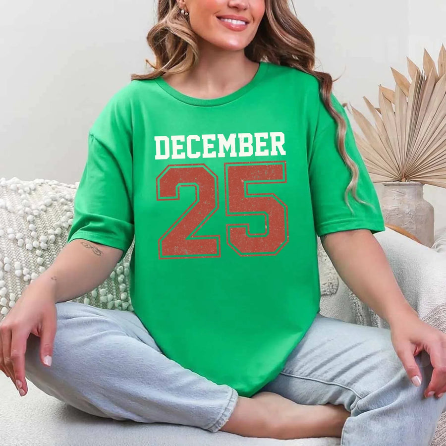 May include a retro-style Christmas sweatshirt featuring bold varsity lettering that reads “December 25” in green and red. The design has a vintage, slightly distressed look, giving it a nostalgic holiday feel perfect for festive winter wear.