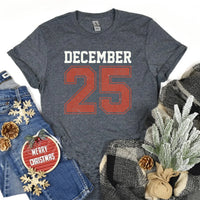 May include a retro-style Christmas sweatshirt featuring bold varsity lettering that reads “December 25” in green and red. The design has a vintage, slightly distressed look, giving it a nostalgic holiday feel perfect for festive winter wear.