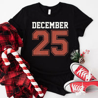 May include a retro-style Christmas sweatshirt featuring bold varsity lettering that reads “December 25” in green and red. The design has a vintage, slightly distressed look, giving it a nostalgic holiday feel perfect for festive winter wear.