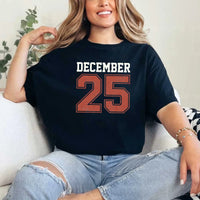 May include a retro-style Christmas sweatshirt featuring bold varsity lettering that reads “December 25” in green and red. The design has a vintage, slightly distressed look, giving it a nostalgic holiday feel perfect for festive winter wear.