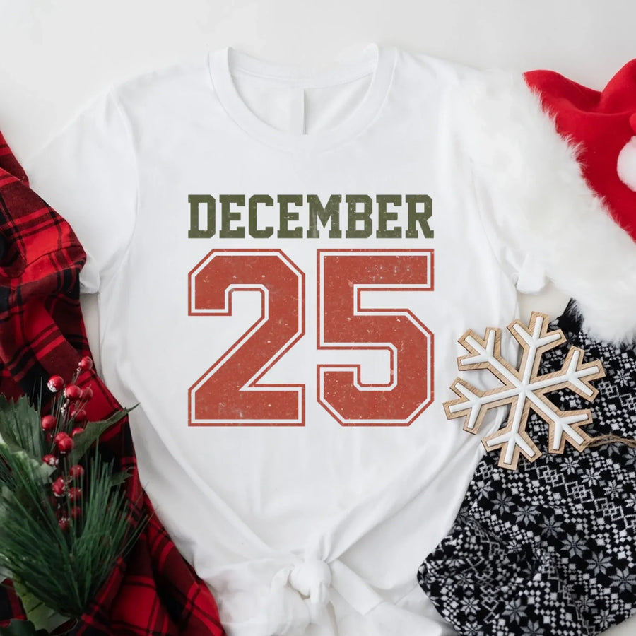 May include a retro-style Christmas sweatshirt featuring bold varsity lettering that reads “December 25” in green and red. The design has a vintage, slightly distressed look, giving it a nostalgic holiday feel perfect for festive winter wear.