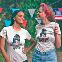 Two women wearing 'All American Mama' graphic tees at outdoor patriotic celebration with flags.