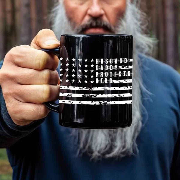 Person holding a black mug with a flag design and text.