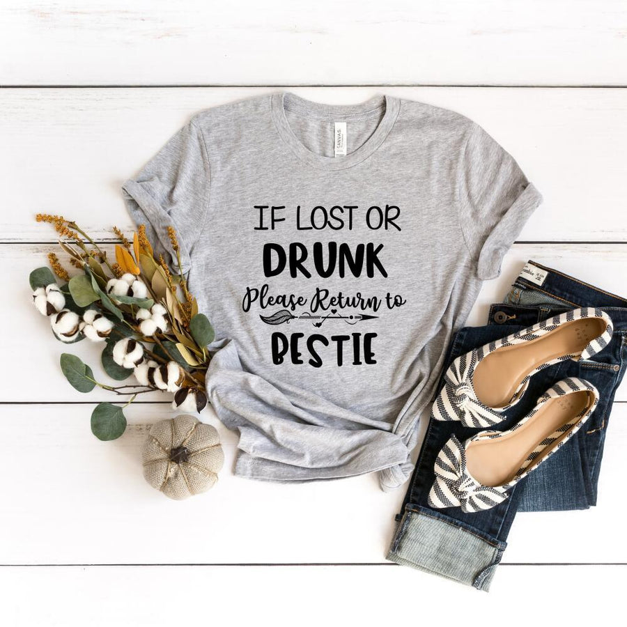 Gray t-shirt with humorous text design on a white wooden surface with accessories.