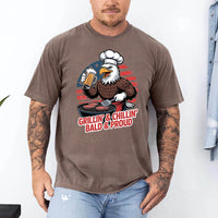 Man wearing a brown t-shirt with an eagle graphic and text, standing against a white background.