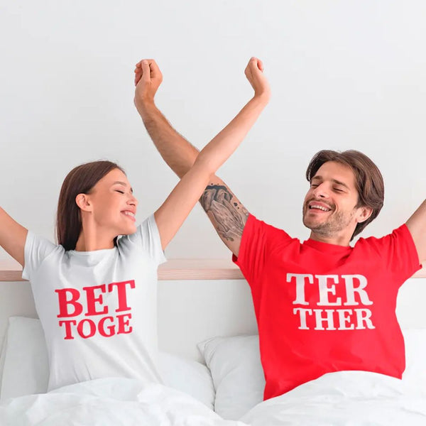 Two people on a bed wearing t-shirts with partially visible text