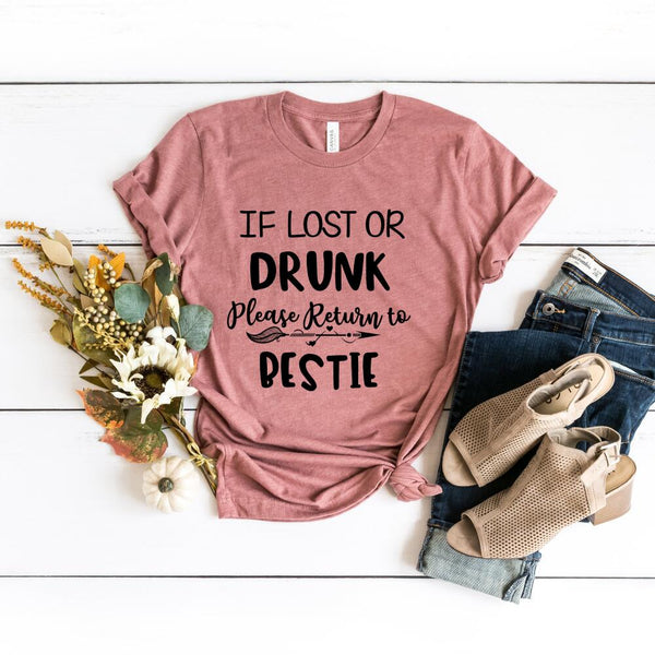 Pink t-shirt with humorous text on a white surface with accessories.