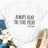 White custom tee with 'Always Read The Fine Print I'm Pregnant' text, flat lay with jeans, roses, and shoes