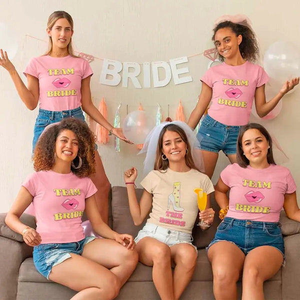 Five women wearing 'Team Bride' t-shirts in a celebratory setting.