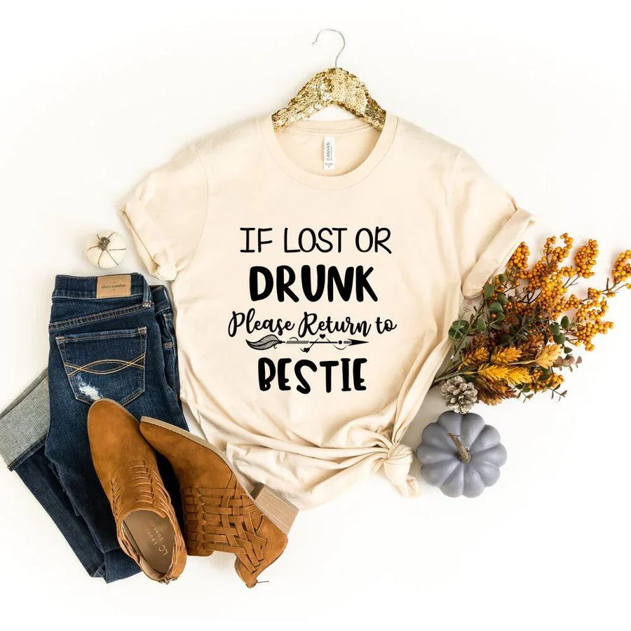 Beige t-shirt with humorous text, jeans, shoes, and decorative items on a white background