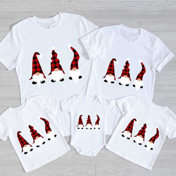 May include a festive holiday t-shirt featuring a cheerful gnome graphic with Christmas-themed details such as a Santa hat, snowflakes, or ornaments. The design conveys a playful and cozy holiday spirit, suitable for seasonal wear or family gatherings.