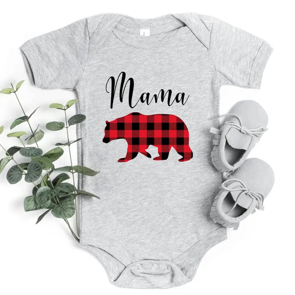 May include matching family t-shirts featuring a Christmas bear design, laid flat with festive decorations and greenery.