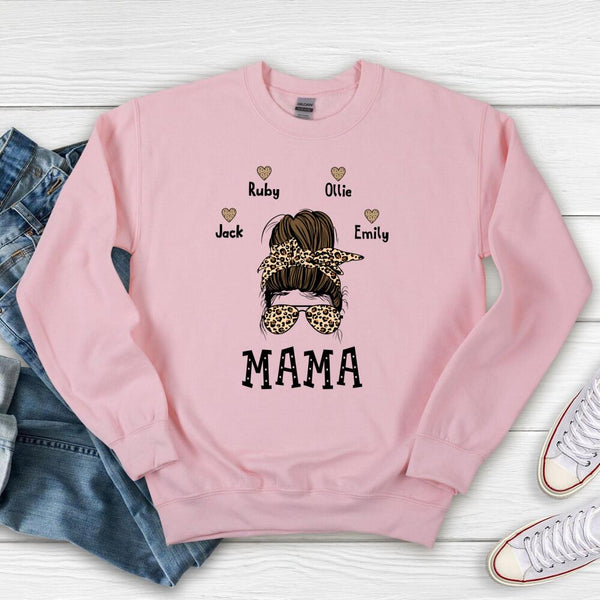 Pink sweatshirt with 'MAMA' and child names on a wooden surface with jeans and sneakers.
