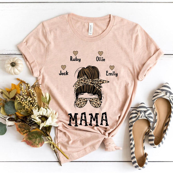Pink t-shirt with 'MAMA' and names printed on it, surrounded by decorative items on a white surface.