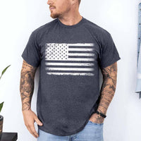 Man wearing a dark gray t-shirt with an American flag design against a white wall.
