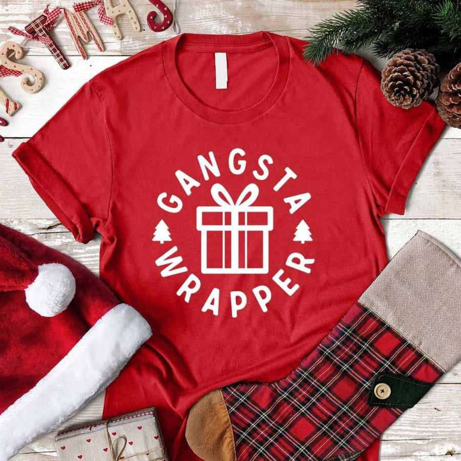 Red Christmas t-shirt with Gangsta Wrapper gift box print, surrounded by holiday decor.