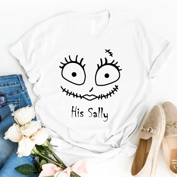 White t-shirt with a face design and text, surrounded by flowers and shoes on a white background