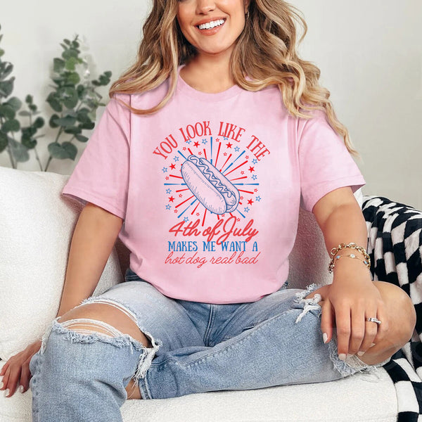 Person wearing a pink t-shirt with a 4th of July graphic, sitting on a couch.