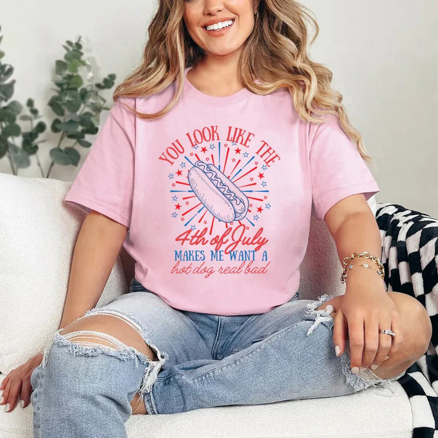Person wearing a pink t-shirt with a 4th of July graphic, sitting on a couch.