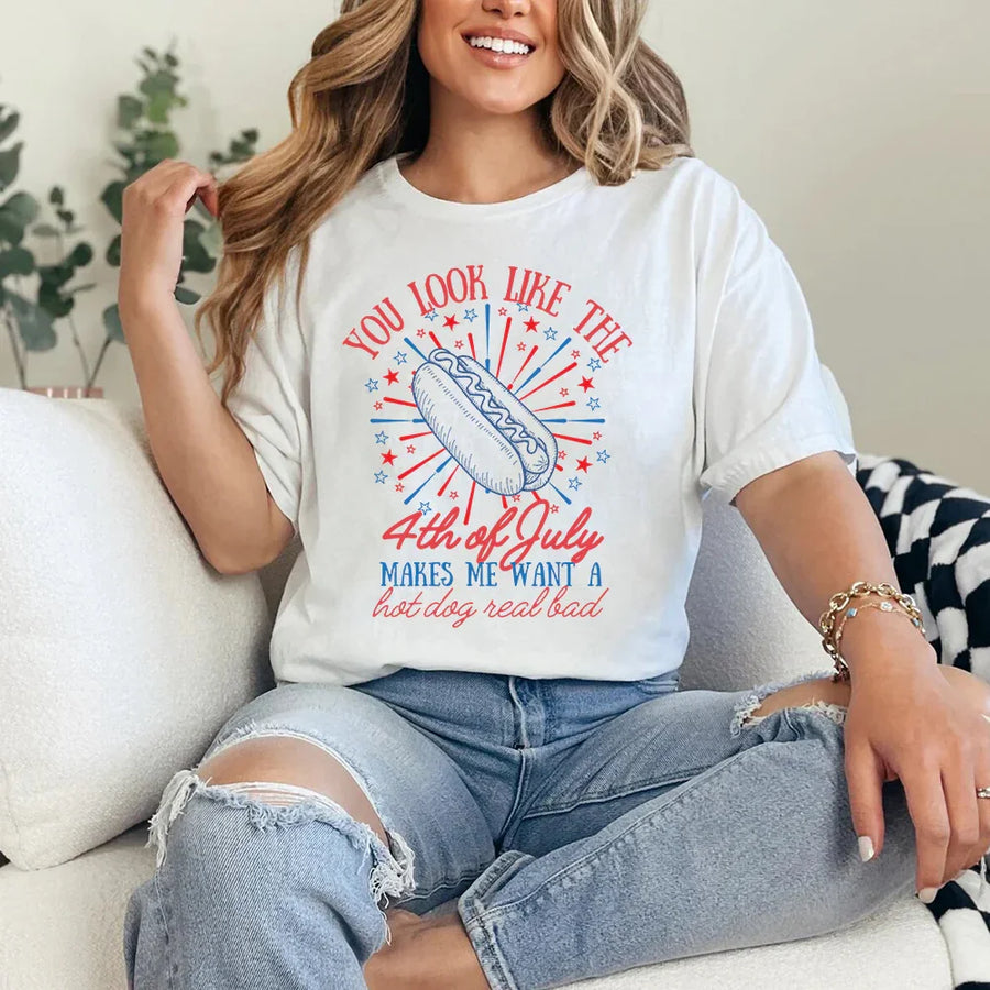 Person wearing a white t-shirt with a colorful graphic and text, sitting on a couch.