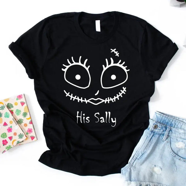 Black t-shirt with a white graphic design and text, placed on a white surface with a notebook and shorts.