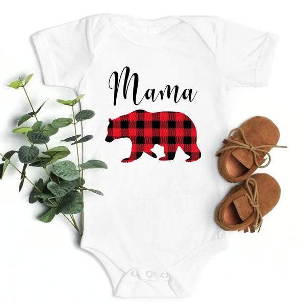 May include matching family t-shirts featuring a Christmas bear design, laid flat with festive decorations and greenery.